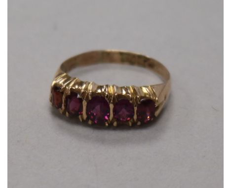 A late Victorian 9ct gold and graduated five stone garnet half hoop ring, size N.