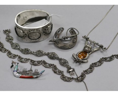 A Victorian engraved silver hinged bangle, a Siamese sterling silver & enamel brooch, amber set monkey pendant, a horseshoe b