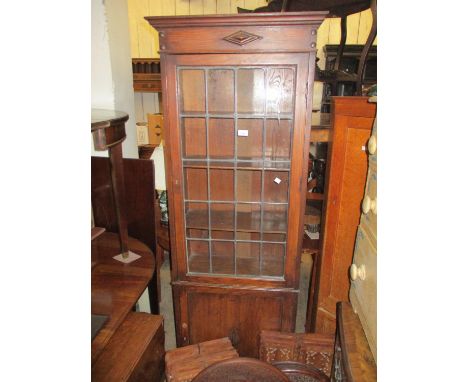 Early 20th Century narrow oak bookcase, the moulded cornice above a lead glazed door with panel door below, raised on bracket