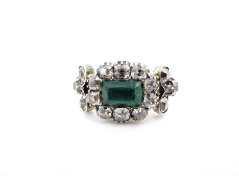 A Georgian emerald and diamond ring, having a central table cut emerald of approximately 8 x 5 mm, framed by ten pinch-set ol