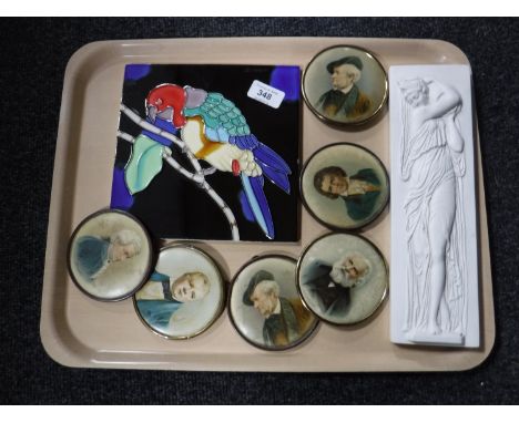 A tray of tubelined tile depicting a parrot, portrait miniatures, relief plaque 