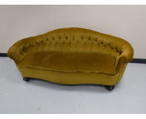 A Victorian low settee upholstered in gold button fabric 