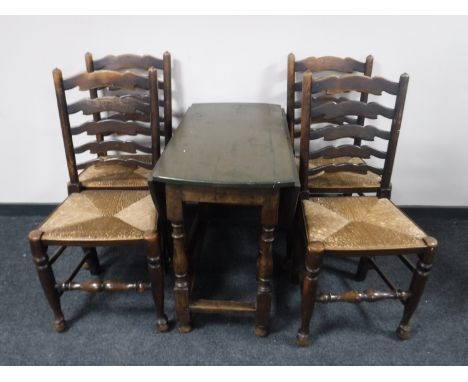 An antique oak gate leg table together with a set of four rush seated ladder back chairs