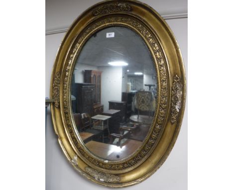A late 19th century ornate oval gilt framed mirror