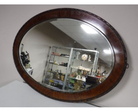 An early twentieth century oval mahogany framed bevelled mirror 