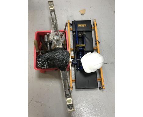 A crate of hand tools, a spirit level, hard hat, car inspection trolley and car jack 