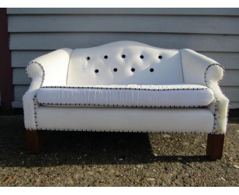 A teddy bear sofa in white button back upholstery, raised on fluted legs, originally purchased at Harrods 