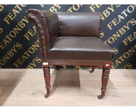 A VICTORIAN CORNER CHAIR UPHOLSTERED IN LEATHER EFFECT CANVAS RAISED ON TURNED MAHOGANY LEGS TERMINATING IN CERAMIC CASTORS