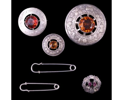 A Scottish-style silver thistle brooch set with amethyst-coloured paste stones, together with three Scottish plaid-type brooc