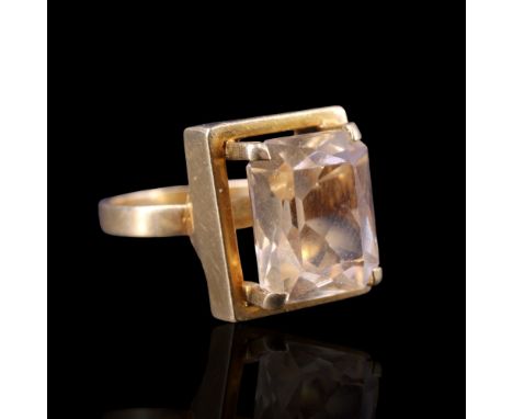 A topaz finger ring, the rectangular-cut stone of approx 12 x 10 mm, claw-set above a conforming 18 ct yellow metal collar, J