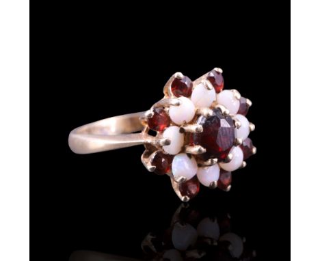 A 1970s opal and garnet cluster ring comprising a central round-cut stone of approx 6 mm diameter, claw-set above terraces of