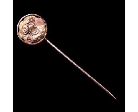 A Belle Epoque style 18 ct yellow metal stick pin, its circular terminal being a relief portrait bust of a fashionably attire