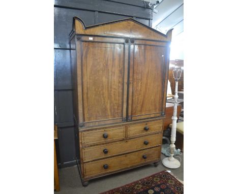 A Georgian mahogany and ebonised linen press cabinet with architectural cornice over two panelled doors opening to a void int