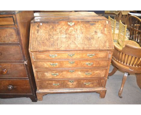 An early Georgian walnut bureau of typical form with full front opening to an interior with small drawers, pigeon holes and a