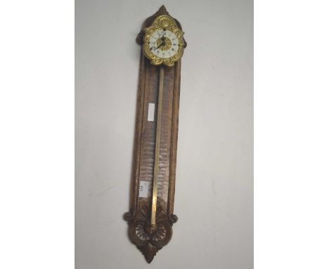 A 20th Century ratchet clock with pressed brass and enamel face and wagging tail pendulum set on a floral carved hardwood bac