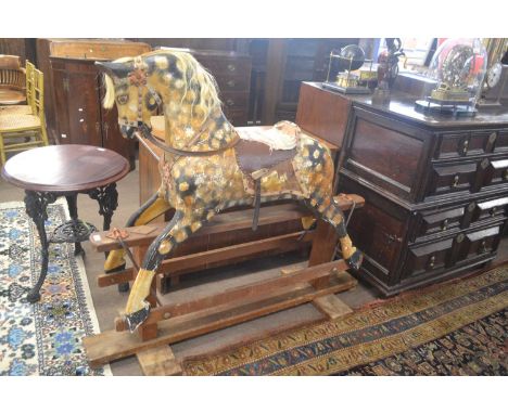 A Victorian rocking horse painted in a dappled design raised on a wooden support with iron fittings, no makers name apparent,