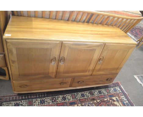 An Ercol light elm low sideboard with three panelled doors over two drawers, 128cm wide