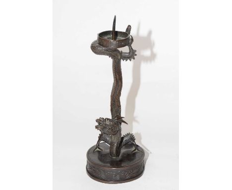 A Chinese metal candlestick shaped as a dragon on circular base, 19cm high