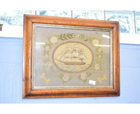 Framed 19th Century "Forget Me Not" embroidery of an 18th Century warship within floral borders in light oak frame