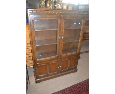 An Ercol dark elm bookcase cabinet with two glazed doors over two panelled doors, 101cm wide