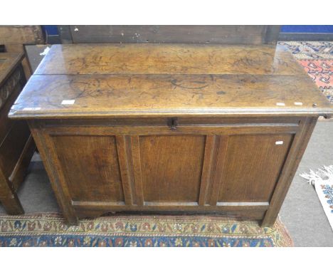 18th Century oak coffer with plank top, opening to a void interior, over a plain three panelled front and style feet, 104cm w