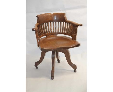 An early 20th Century oak desk chair with bow back and saddle formed seat set on a four footed revolving base, 82cm high