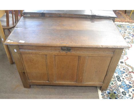 An 18th Century oak coffer with plank top opening to an interior with candle box, over a three panelled front, raised on styl