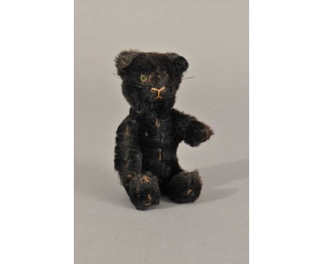 A Schuco Teddy bear perfume bottle, c1920s, with inset glass eyes and jointed limbs, the head lifting to reveal a glass flask