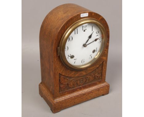 An oak cased mantle clock with carving details. 