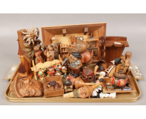 A tray of carved wooden figures and bottle tops, along with an enamel lapel badge and inset pendant. 