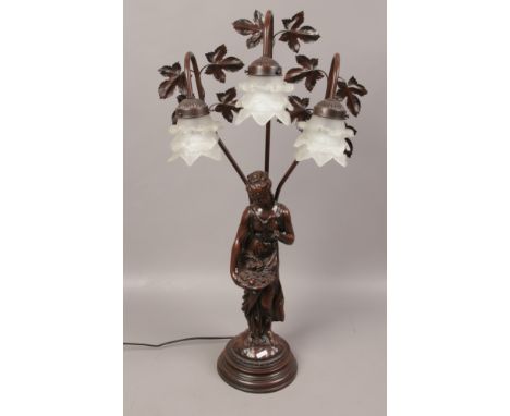 A bronzed composite twin branch figural table lamp formed as a fruit seller. 