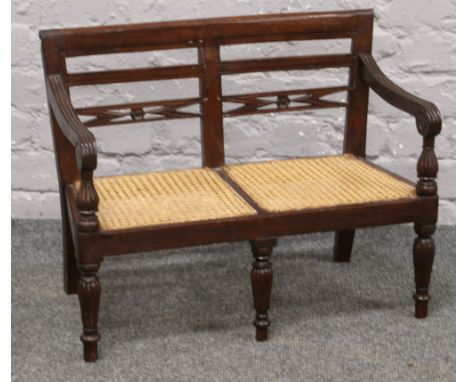 A Regency style carved mahogany and canework two seat child's bench raised on reeded legs. 