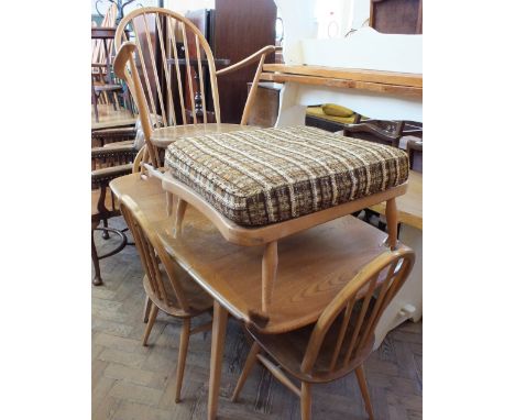 An Ercol drop leaf dining table with four chairs and another Ercol armchair with foot stool