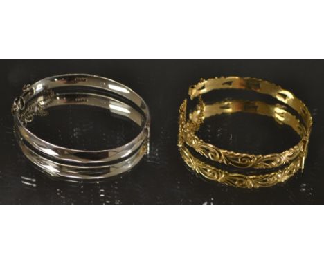 An ornate cast rolled gold hinge bangle, unmarked; a silver hinged bangle (2)