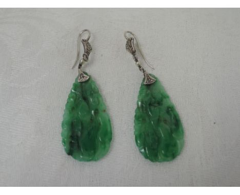 A pair of carved jade drop earrings of teardrop form having white metal fittings