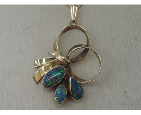 A black opal doublet pendant having collared mounts in a loop and bow yellow metal setting stamped 9ct on a yellow metal chai