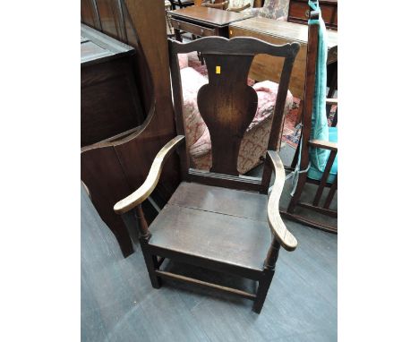 A late 18th century oak vernacular hall/armchair having vase back with solid seat and tapered legs 