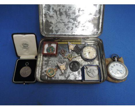 A tin box containing Land Army badges, military medallions and pocket watches