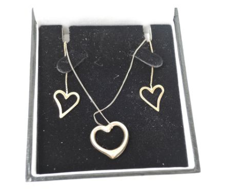 A yellow metal hollow heart pendant on a 9ct gold chain with matched 9ct gold heart earrings on chain drops