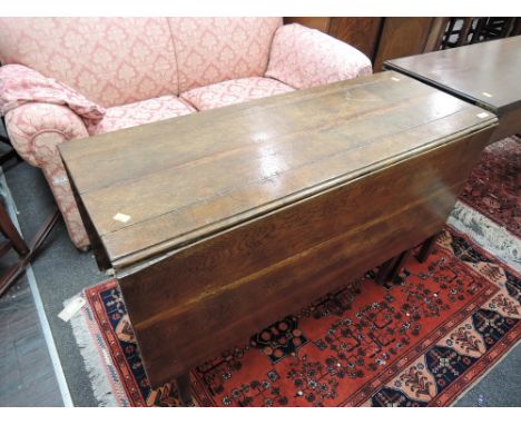 An early 19th century oak dining table having drop leaf top and frieze drawers on square gate legs