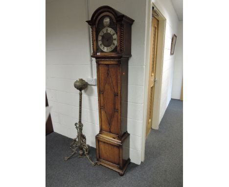 A mid 20th century oak grandmother clock having arch hood with brass face and silvered dial on applique trunk and square base