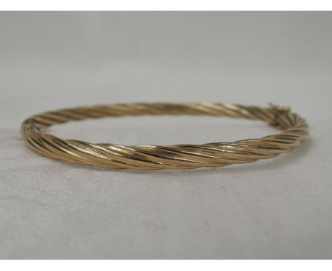 A yellow metal hinged bangle having twist decoration, approx 7.1g, no marks tested as 9ct gold