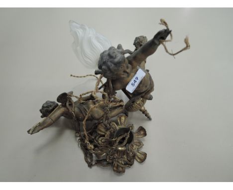 A vintage brass ceiling light modelled as three hanging cherubs with flame glass shade
