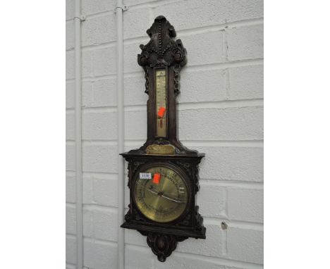 A mid 20th century oak aneroid barometer having thermometer scale, carved decoration with presentation plaque for Mr Norton, 