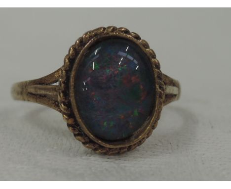 A lady's dress ring having an oval black opal doublet  in a collared mount with gold wire decoration to 9ct gold loop