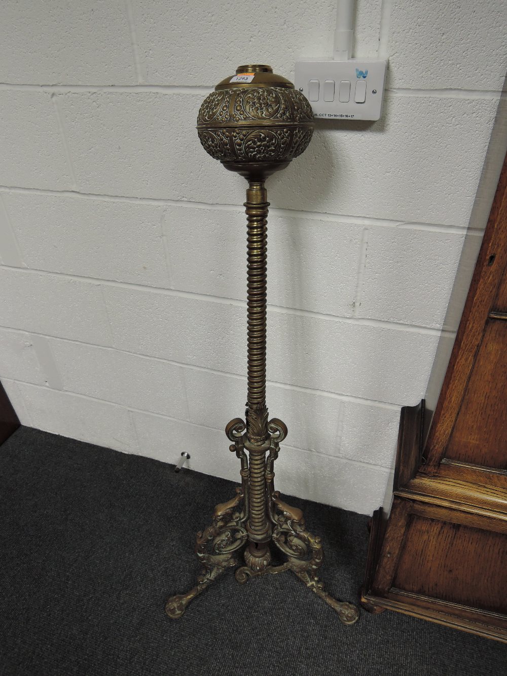 A late Victorian brass oil lamp stand having embossed reservoir and