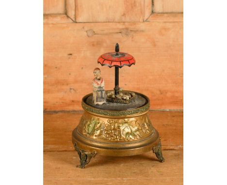 A GERMAN ART DECO CLOCK MODELLED AS A FIGURE UNDER A PARASOLEarly 20th Century
The circular gilt metal base surmounted by a s