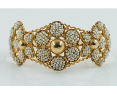 A GOLD AND SEED PEARL BANGLEThe front formed as floral clusters with three hemispherical divisions at intervals, gross weight
