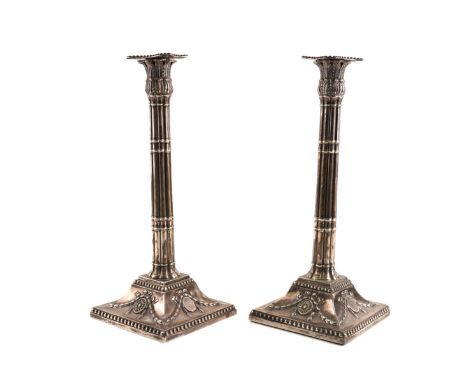 A PAIR OF SILVER TABLE CANDLESTICKSEach with a fluted column, foliate decorated, classical tops and raised on swept square ba