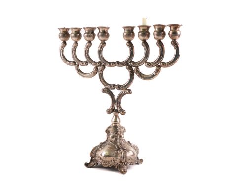 AN ISRAELI EIGHT LIGHT MENORAHThe curved arms with floral decoration, raised on a shaped base, having four scrolled feet, det